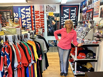 Jo Anne Price stands amongst her Trump themed items. Notice the gold Trump sneakers at center left of the photo.